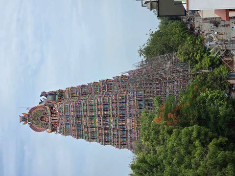 Vibrantly painted towering gopuram of Meenakshi style temple surrounded by scaffolding.