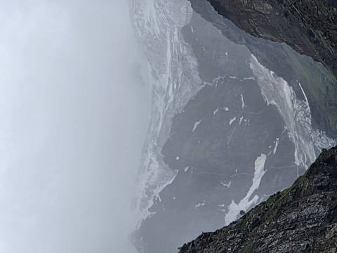 Cloud-covered glacial peaks with rugged valley below.