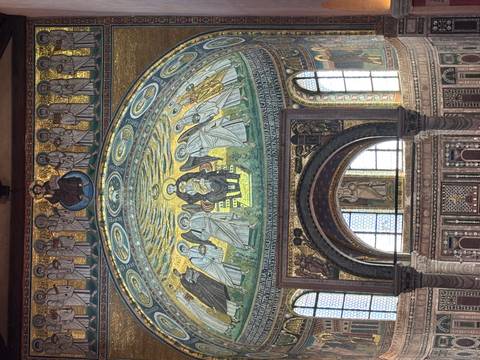 Glittering Byzantine-style mosaic dome depicting saints inside a historic basilica.