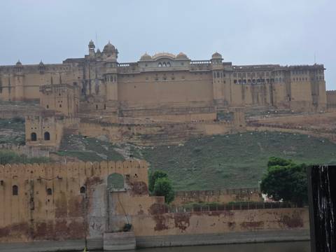 Expansive view of Amber Fort’s massive tan walls perched on a hillside in monsoon haze.