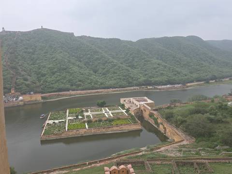 Elevated view of Moata Lake’s geometric garden island surrounded by forested hills beside Amber Fort.