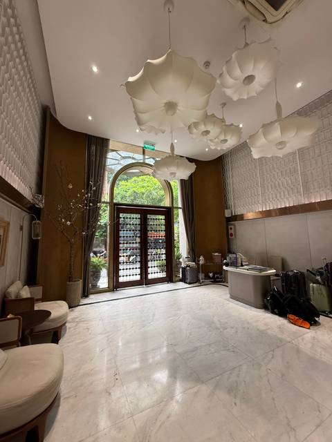 Chic hotel lobby with high ceiling, modern chandeliers, and luggage near the reception desk