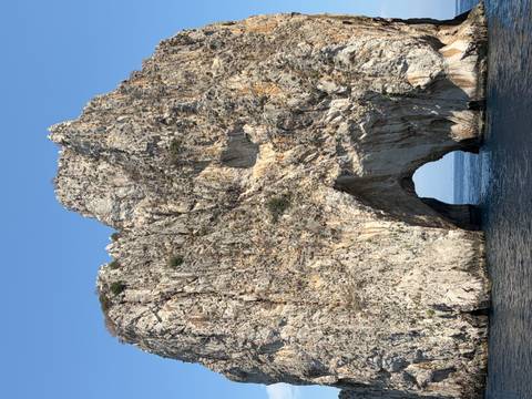 Massive limestone arch rising from the sea, part of the famous Faraglioni rock formations