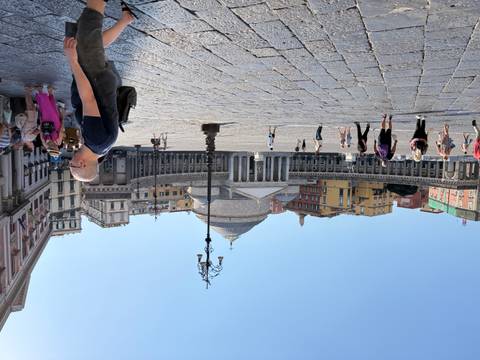 Large open square of Piazza del Plebiscito in Naples with classical dome and columns, visitors strolling