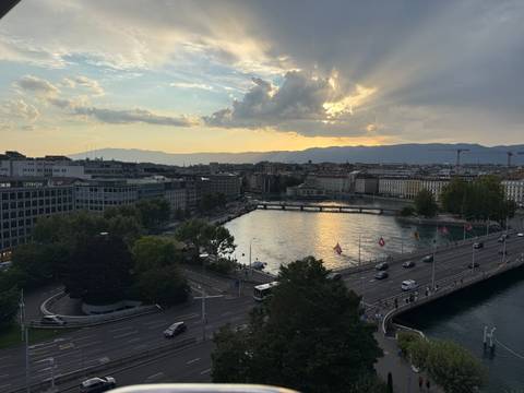 Aerial view of Geneva cityscape and lake at dusk with dramatic clouds and sun rays