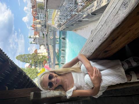 Smiling girl on Lucerne's Chapel Bridge with river, historic buildings, and sunny sky behind