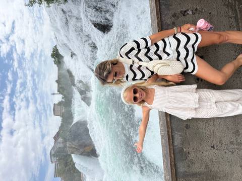 Mother and daughter posing with Rhine Falls thundering in the background