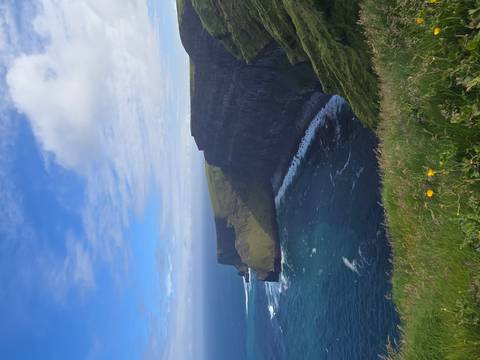 Dramatic sea cliffs drop into deep blue Atlantic waters under a patchwork sky at the Cliffs of Moher.
