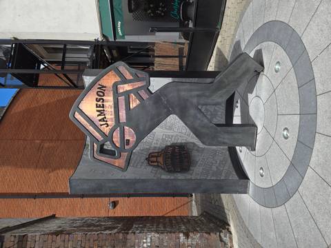Modern metal sculpture and wall celebrating Jameson Whiskey outside the distillery in Dublin.
