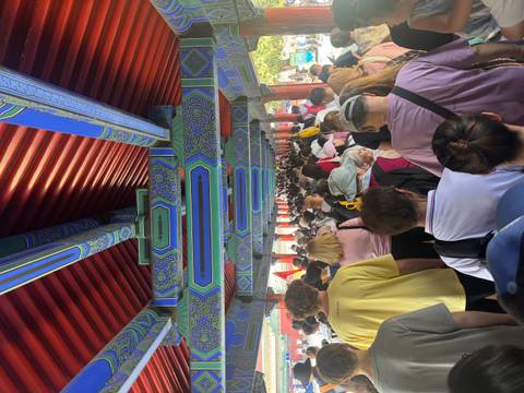 Mass of visitors under ornate painted corridor roof inside Beijing’s Forbidden City.