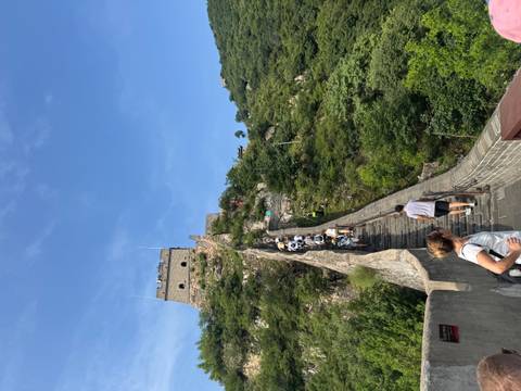 Tourists climbing steep stone stairs on remote section of the Great Wall beneath blue sky.