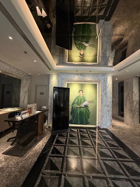 Marble-clad hotel lobby featuring a large portrait of a woman in green traditional dress.