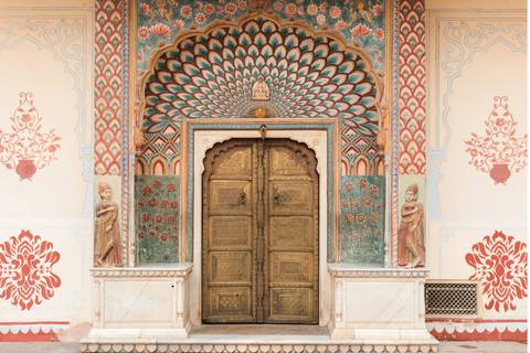 Vibrant Peacock Gate at Jaipur City Palace with ornate teal and gold motifs framing a bronze door.