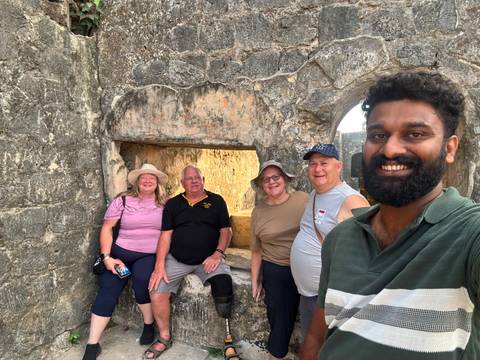 Smile-filled selfie of travellers inside stone ruins with arched windows