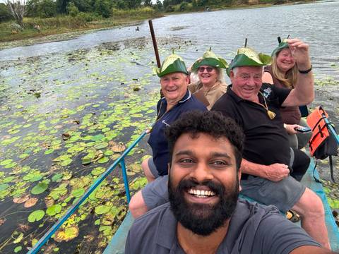 Boat selfie of travellers wearing playful leaf hats gliding over lily-covered lake