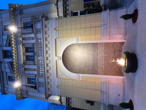 Eternal Flame war memorial set in an arched niche of a neoclassical building lit at dusk