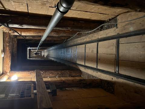 Wood-lined underground tunnel with narrow gauge tracks stretching into darkness