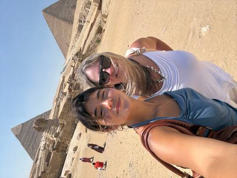Wind-swept mother and daughter selfie with the Sphinx and a pyramid in the bright desert sun