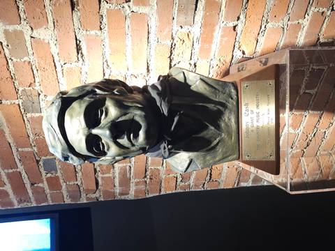 Bronze bust of Johnny Cash displayed against an exposed brick wall inside a music museum.
