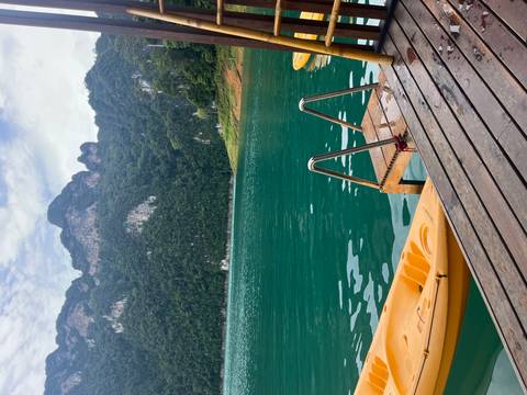 Wooden dock with kayak and ladder leading into turquoise lake surrounded by towering jungle cliffs