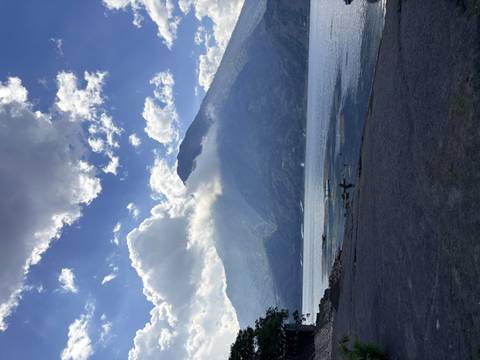 Cloud-capped volcano rises above the calm blue waters of Lake Atitlán under a dramatic sky.