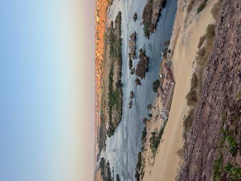 Wide view over the Nile River with sandy banks, small islands and distant city at sunset