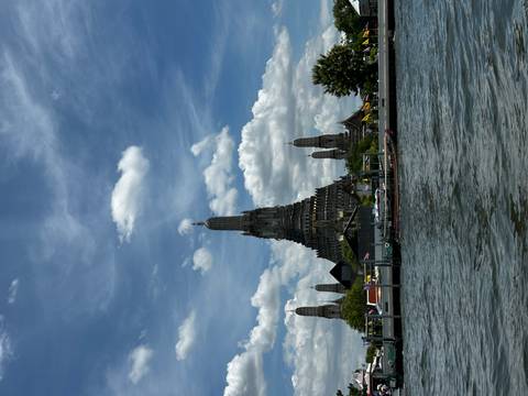 Wat Arun’s prang rising above the Chao Phraya River seen from a boat on a sunny afternoon
