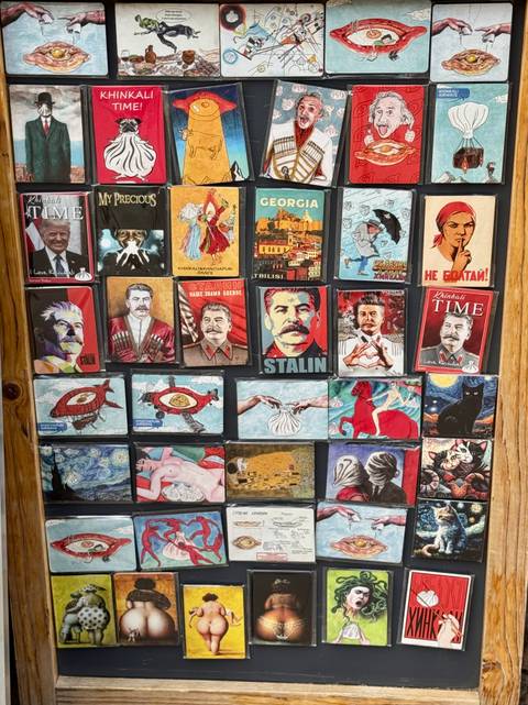 Display board filled with colourful souvenir magnets depicting Soviet imagery and Georgian themes