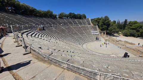 Wide view of the perfectly preserved Ancient Theatre of Epidaurus with concentric stone seating.