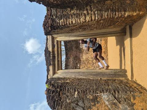 Traveler playfully suspended in mid-air within a stone doorway of ancient Sri Lankan ruins.