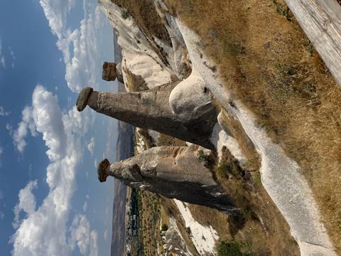 Three distinctive fairy-chimney rock pillars rise from Cappadocia’s dry grasslands.