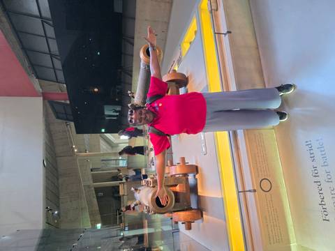 Visitor with arms spread inside a museum hall featuring historic cannons and interactive exhibits.