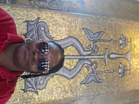 Selfie in front of a detailed golden mosaic artwork inside an ornate hall.