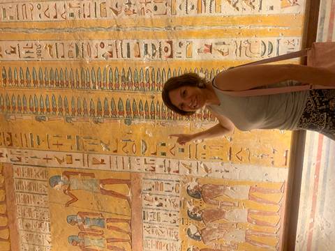 Visitor points at colorful hieroglyphics inside an ancient Egyptian tomb