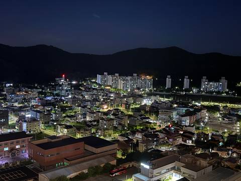 Night cityscape with illuminated residential buildings and dark surrounding hills