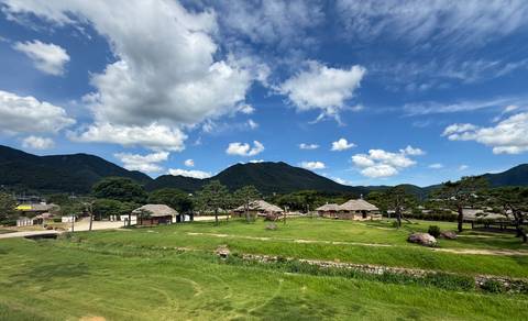 Traditional Korean folk village of thatched houses set among green mountains and blue sky