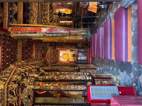 Lavishly decorated temple interior with gold carvings and cushioned kneeling benches