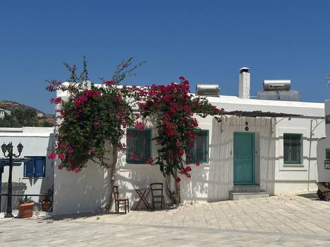 Charming whitewashed island house with turquoise accents and blooming bougainvillea.