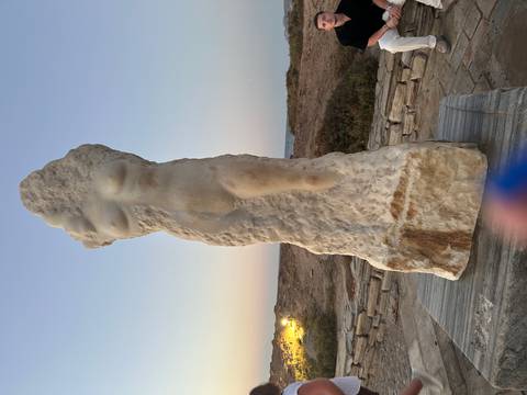 Marble modernist statue of a female form displayed outdoors at dusk.
