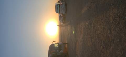 Sun setting over desert highway with parked tour buses and silhouetted travelers