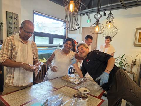 Participants laugh together during a hands-on cooking class in a bright kitchen