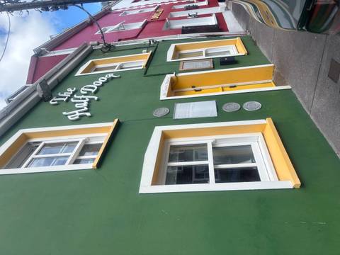 Colorful green and yellow façade of ‘The Half Door’ pub on a village street.