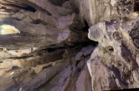 Jagged cave ceiling with dramatic rock formations lit by artificial lights.