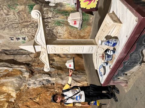 Stone balance scale altar with Chinese characters inside a cave shrine.