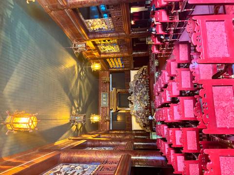 Ornate wooden theatre hall with rows of red chairs and golden lanterns inside Hue’s citadel.