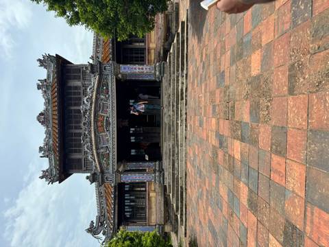 Visitor ascending stone steps toward elaborately carved ancient gate of Hue Citadel.