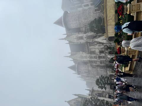 Medieval-style stone castle shrouded in mist with visitors in foreground at Ba Na Hills.