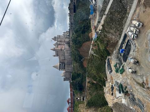 Hilltop fantasy castle of Ba Na Hills seen from cable car with construction site below.
