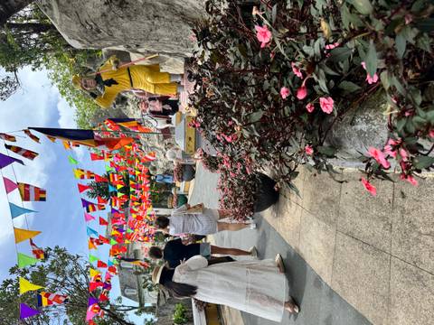 Colorful flag-lined pathway crowded with visitors and playful statues at Ba Na Hills festival area.