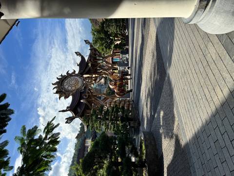 Artistic wooden sun-shaped gate structure leading into plaza under blue sky at Ba Na Hills.